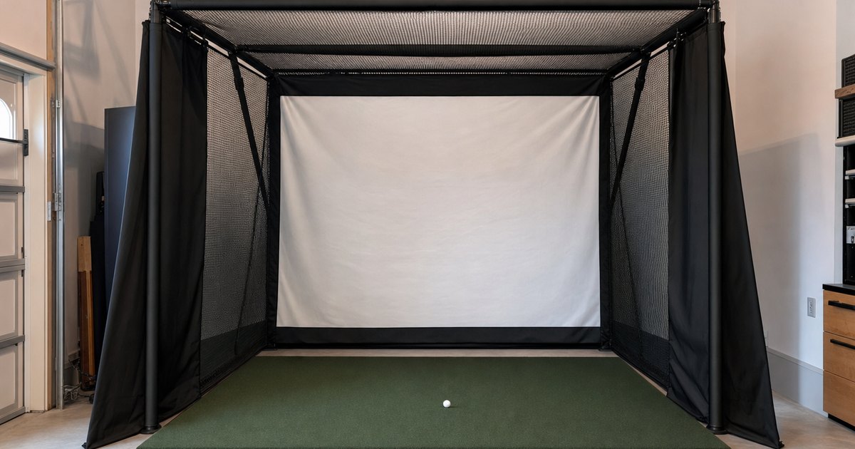 A golf simulator enclosure with a hitting net and turf mat in a garage.